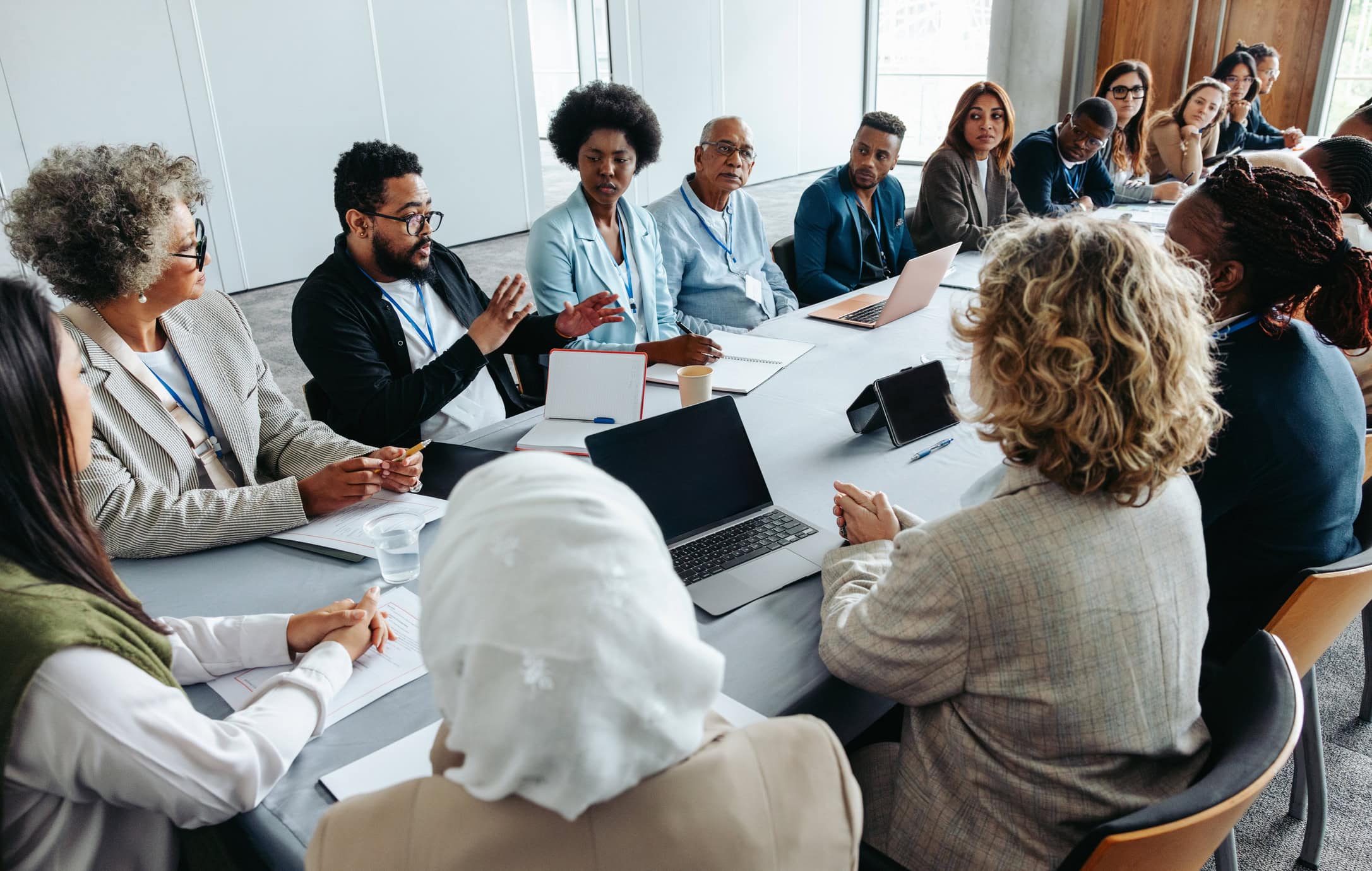 Multiethnic group of businesspeople engaged in a strategy and brainstorming session around a conference table. Collaborative and focused on teamwork and planning.